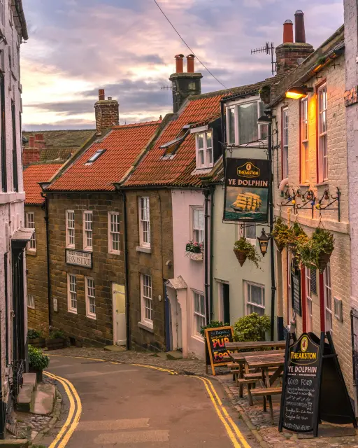 A pretty British street on a hill, with a pub on the right